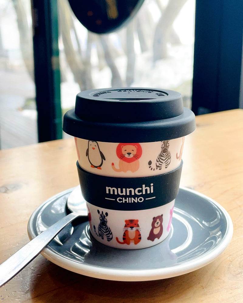 kids zoo print babychino cup with lion, zebra, tiger, bear, pig and penguin in cafe