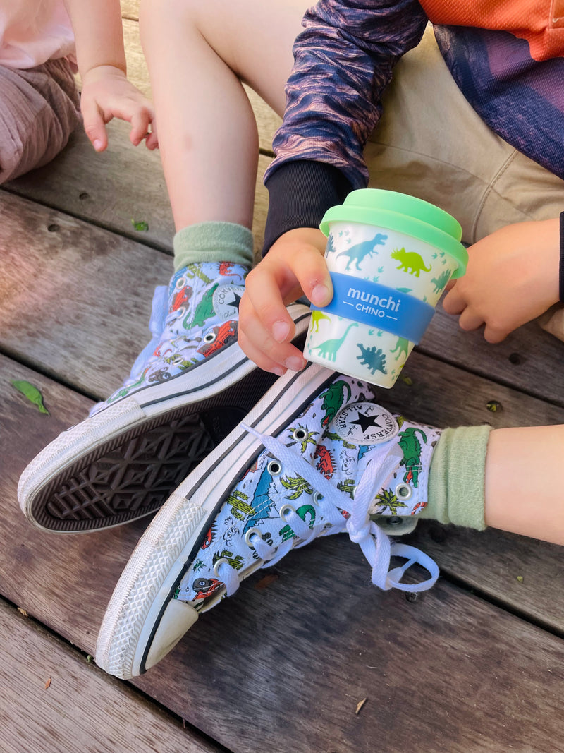 boy holdiing dinosaur babycino cup converse