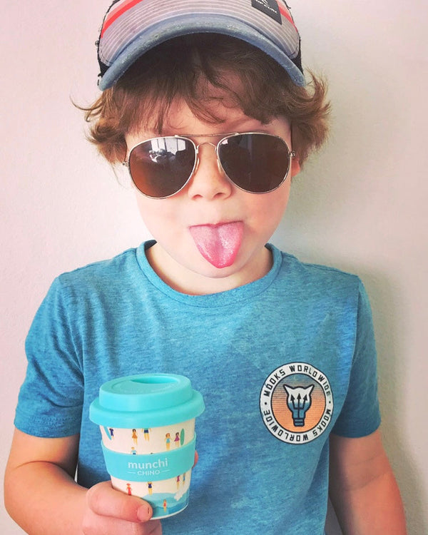 boy with blue aqua beach babycino cup poking tongue out